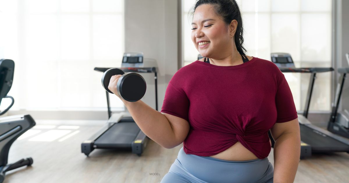 woman lifting dumbbell, attempting to loose weight before her plastic surgery (model)